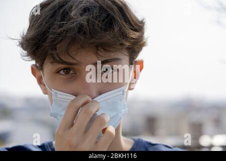 Nahaufnahme von Teenager Junge trägt blaue chirurgische Maske im Freien Stockfoto