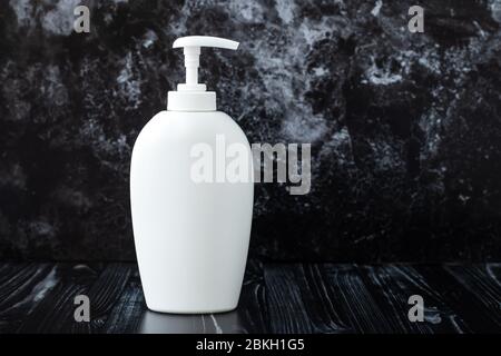 Weiße Flüssigseife auf schwarzem Marmorgrund im Badezimmer. Konzept der Hygiene. Spender Kunststoffflasche. Text, Kopierbereich. Produkt von kosmetischen Stockfoto