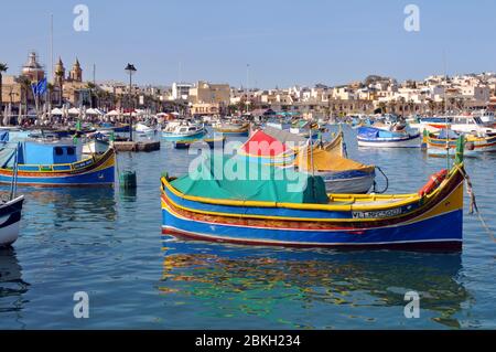Bunte maltesische Fischerboote im geschützten Hafen von Marsaxlokk, Malta. Seit Jahrhunderten bewohnt, ist das Dorf ein beliebtes Touristenziel. Stockfoto