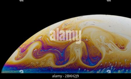 Nachahmung der Oberfläche des Planeten. Teil der Seifenblase. Nahaufnahme. Wunderschöne Muster. Schwarzer Hintergrund. Leuchtende Farben. Das Thema der Wissenschaft f Stockfoto