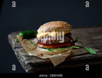 Frischer, leckerer Burger auf einem alten dunklen Holztisch Stockfoto