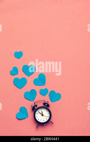 Wecker und Herzen auf farbigem Hintergrund. Platz für Text. Stockfoto