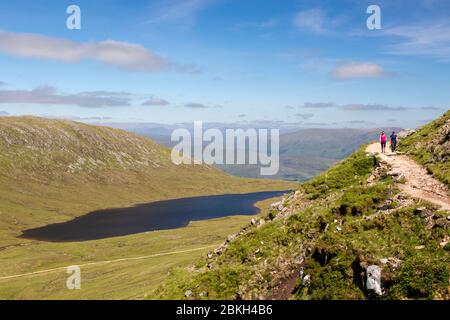 Zwei Wanderer auf einem Wanderweg mit einem See (Lochan Meall an T-suidhe) hinter, auf Ben Nevis, Scottish Highlands, Schottland Stockfoto