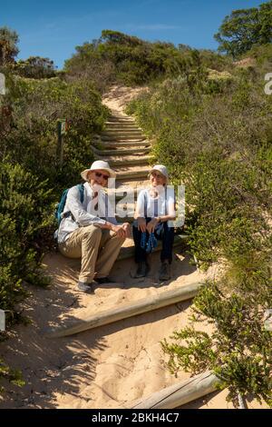 Südafrika, Western Cape, Plettenberg Bay, Robberg Nature Reserve, The Gap, Senioren Touristen ruhen auf Küstenwanderweg Stockfoto