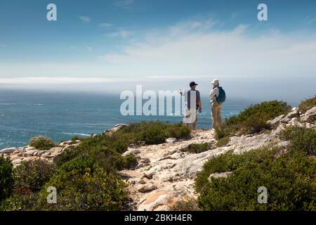 Südafrika, Western Cape, Plettenberg Bay, Robberg Nature Reserve, Cape Seal, Senioren Touristen ruhen auf Küstenwanderweg über felsigen Küste Stockfoto