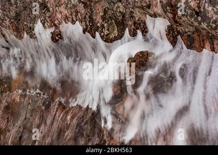 Eisvorhänge auf den Klippen des Tettegouche State Park, wo die Wellen des Lake Superior gegen den Felsen schlagen und eine Wasserschicht hinterlassen, die gefrierte Stockfoto