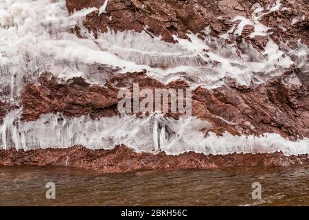 Eisvorhänge auf den Klippen des Tettegouche State Park, wo die Wellen des Lake Superior gegen den Felsen schlagen und eine Wasserschicht hinterlassen, die gefrierte Stockfoto