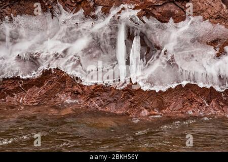 Eisvorhänge auf den Klippen des Tettegouche State Park, wo die Wellen des Lake Superior gegen den Felsen schlagen und eine Wasserschicht hinterlassen, die gefrierte Stockfoto