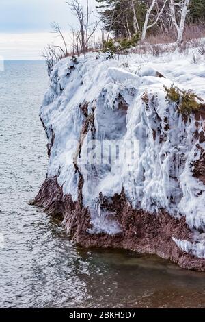 Eisvorhänge auf den Klippen des Tettegouche State Park, wo die Wellen des Lake Superior gegen den Felsen schlagen und eine Wasserschicht hinterlassen, die gefrierte Stockfoto