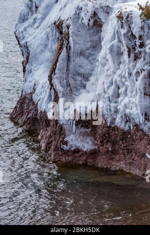 Eisvorhänge auf den Klippen des Tettegouche State Park, wo die Wellen des Lake Superior gegen den Felsen schlagen und eine Wasserschicht hinterlassen, die gefrierte Stockfoto