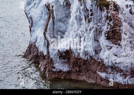 Eisvorhänge auf den Klippen des Tettegouche State Park, wo die Wellen des Lake Superior gegen den Felsen schlagen und eine Wasserschicht hinterlassen, die gefrierte Stockfoto