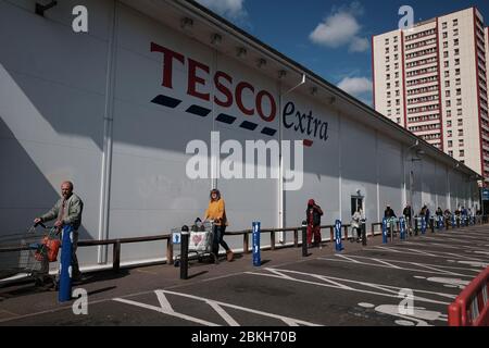 Die Menschen üben soziale Distanz, während sie vor einem Tesco Extra-Laden in Twickenham, London, Schlange stehen, während Großbritannien weiterhin in der Lockdown-Funktion ist, um die Ausbreitung des Coronavirus einzudämmen. Stockfoto