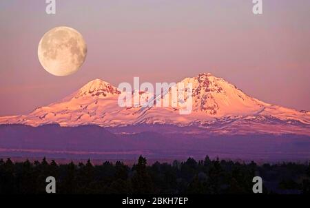 Eine Vollmond-Kulisse über den Three Sisters Peaks in den Oregon Cascade Mountains in der Nähe von Bend, Oregon. Stockfoto