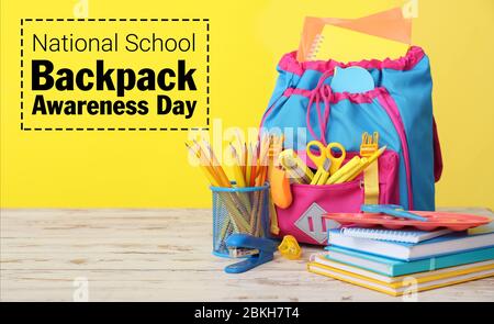 Schultasche und Schreibwaren auf dem Tisch vor farbigem Hintergrund. National School Backpack Awareness Day Stockfoto