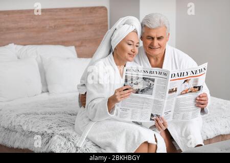 Ältere paar lesen Zeitung im Schlafzimmer Stockfoto