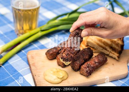 Mici Cu bere traditionelle rumänische Gericht für die Feierlichkeiten der 1. Mai der Tag der Arbeit. Treffen Bälle Fleisch Brötchen Gericht und Bier türkischen Kofte Stockfoto