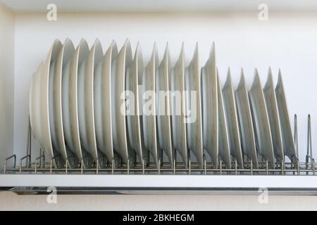 Regal für Geschirr Trocknen in der modernen Küche. Geschirr aus weißem Glas und Keramik auf Metallgestell im Küchenschrank. Stockfoto