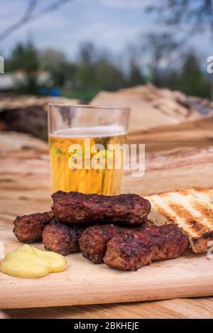 Mici Cu bere traditionelle rumänische Gericht für die Feierlichkeiten der 1. Mai der Tag der Arbeit. Treffen Bälle Fleisch Brötchen Gericht und Bier türkischen Kofte Stockfoto