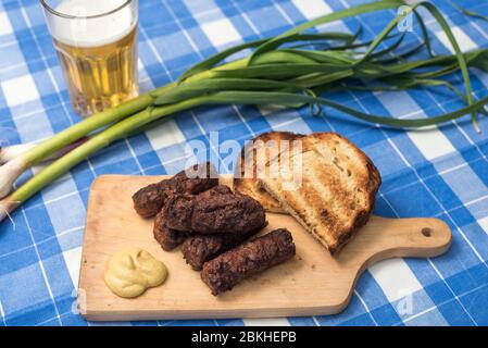 Mici Cu bere traditionelle rumänische Gericht für die Feierlichkeiten der 1. Mai der Tag der Arbeit. Treffen Bälle Fleisch Brötchen Gericht und Bier türkischen Kofte Stockfoto