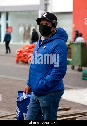 Mann, der eine Gesichtsmaske trägt, wagt sich während der COVID-19 Pandemie zum Zentrum von Lewisham, um seine wichtigsten Lebensmittel einzukaufen. Stockfoto