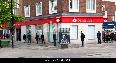 Kunden, die strenge soziale Distanz beobachten, müssen während der COVID-19 Pandemie geduldig in die Santander Bank in der Lewisham Hight Street eintreten Stockfoto