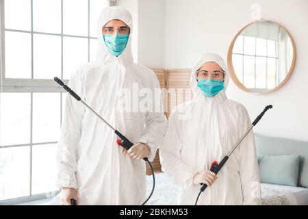 Arbeiter in Biogefährdungsanzügen desinfizierenden Haus Stockfoto