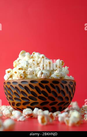 Nahaufnahme von Popcorn in einer Schüssel auf rotem Hintergrund. Stockfoto