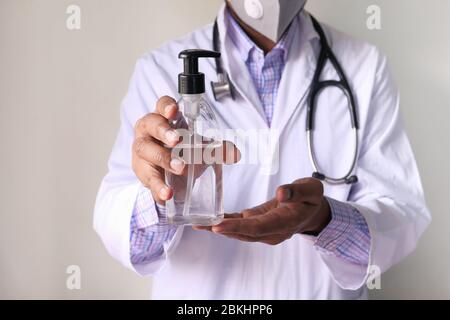 Arzt mit Gesichtsmaske mit Handdesinfektionsmittel Stockfoto