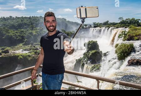 Mann nimmt ein Selfie mit Monopod an den Iguazu Wasserfällen in Argentinien Stockfoto