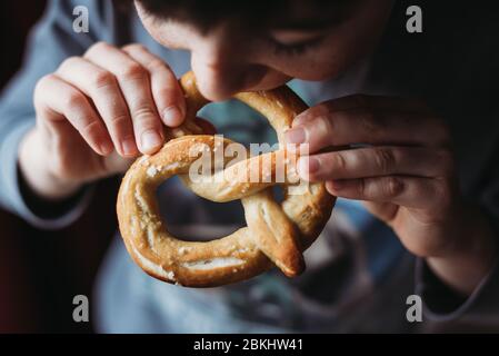 Nahaufnahme des Jungen essen eine weiche hausgemachte Brezel. Stockfoto