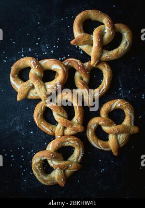 Draufsicht auf hausgemachte weiche Brezeln auf schwarzem Hintergrund. Stockfoto