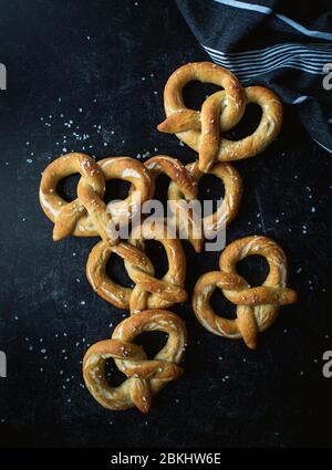 Draufsicht auf hausgemachte weiche Brezeln auf schwarzem Hintergrund. Stockfoto