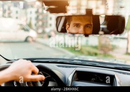 Ein Mann schaut aus dem Heckfenster. In seinem Auto. Transportkonzept Stockfoto