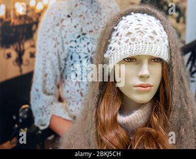 Weibliche Schaufensterpuppe in einem weißen Strickmütze und einem Daunenschal. Stockfoto