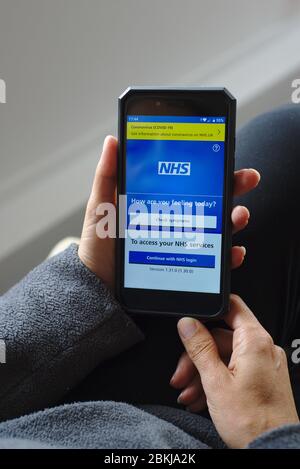 NHS-App auf Smartphone Coronavirus COVID-19 Link und Symptome zu überprüfen. Stockfoto