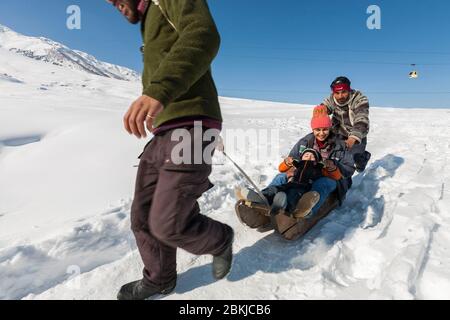 Indien, Jammu und Kaschmir, Gulmarg, Familie von indischen Touristen, die Spaß auf einem Schlitten von einem lokalen Kashmiri Führer gezogen, in Kongdoori, erste Station der Gondelbahn, Höhe 3090 Meter Stockfoto