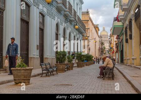 Kuba, Havanna, Bezirk La Habana Vieja, Weltkulturerbe der UNESCO, kubaner rauchen eine Zigarre auf einer Bank, im Hintergrund das Kapitol Stockfoto