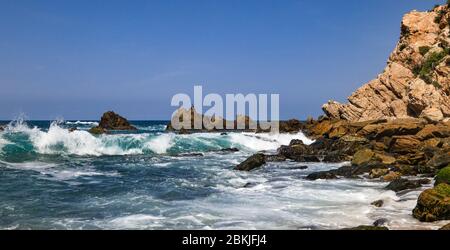 Ein herrlicher Blick auf den Pazifik vom Mayto Beach in Jalisco, Mexiko. Wellen schlagen auf natürlichen Felsformationen. Stockfoto