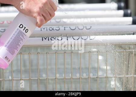 Glasgow, Schottland, Großbritannien. 4. Mai 2020. Ein Mitarbeiter von Marks and Spencer desinfiziert die Griffe von Einkaufswägen außerhalb des Braehead Shopping Centre, Glasgow. Die Weltgesundheitsorganisation hat heute Ratschläge für Käufer herausgegeben, einschließlich wenn möglich, die Griffe von Einkaufswagen oder Körben vor dem Einkaufen zu desinfizieren Kredit: Kay Roxby/Alamy Live News Stockfoto