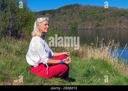 Europa, Luxemburg, Insenborn, attraktive ältere Frau meditierend von Lac Sûre Stockfoto
