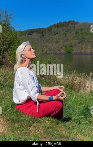 Europa, Luxemburg, Insenborn, attraktive ältere Frau meditierend von Lac Sûre Stockfoto