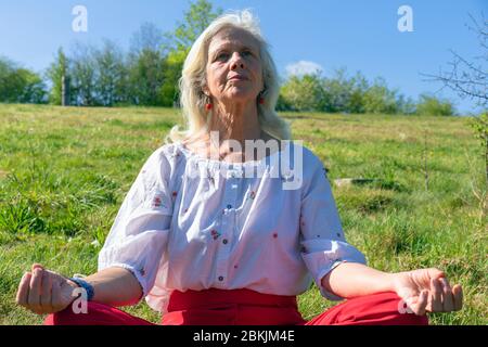 Europa, Luxemburg, Insenborn, attraktive ältere Frau meditiert in der Nähe des Lac Sûre Stockfoto
