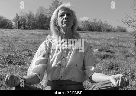 Europa, Luxemburg, Insenborn, attraktive ältere Frau meditiert in der Nähe des Lac Sûre Stockfoto