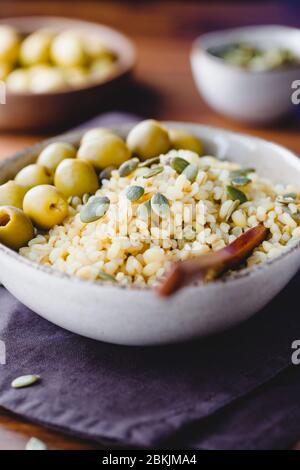 Bulgur mit grünen Oliven und Pepitas, gesunde Ernährung einfach Rezept aus lange gelagerten Lebensmitteln. Stockfoto