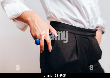 Nahaufnahme der Hand der Frau legt Telefon in die Tasche Stockfoto