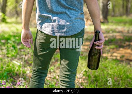 Betrunkener Mann mit einer Flasche Alkohol in der Hand in der Natur Stockfoto