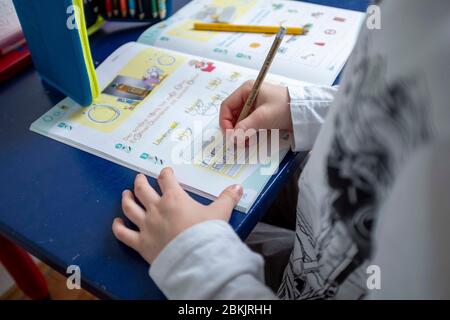 Erstklaessler (7 Jahre) sitzt zu Hause an einem Tisch und erledigt deutsche Aufgaben in seinem Booklet "Alphabet Booklet - BASIC Font", am 4. Mai 2020 in Mülheim an der Ruhr. ¬ Verwendung weltweit Stockfoto