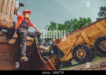 Baggerfahrer, Der Pause Einlegen Und Sich Auf Der Oberseite Der Hochleistungsausrüstung Ausruhen Kann Stockfoto