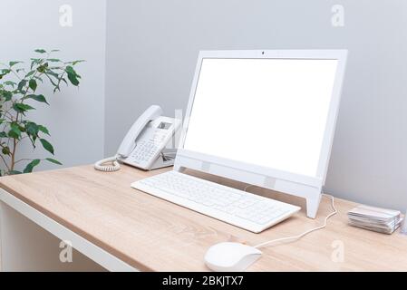 Isoliertes weißes Computerdisplay für den Aufbau auf dem Schreibtisch in einem hellen, gemütlichen Büro mit weißer Computermaus und Telefon. Minimalismus auf dem Desktop Stockfoto