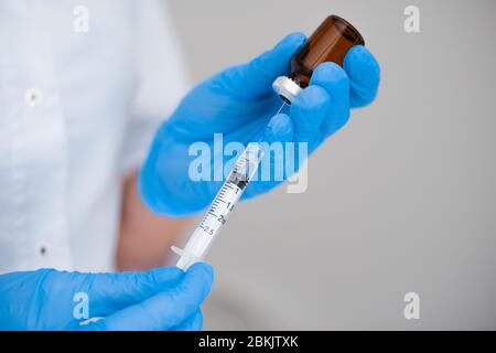 Der Arzt zeichnet eine Nahaufnahme einer Impfstoffinjektion in eine Spritze. Injektionskosmetologie Stockfoto